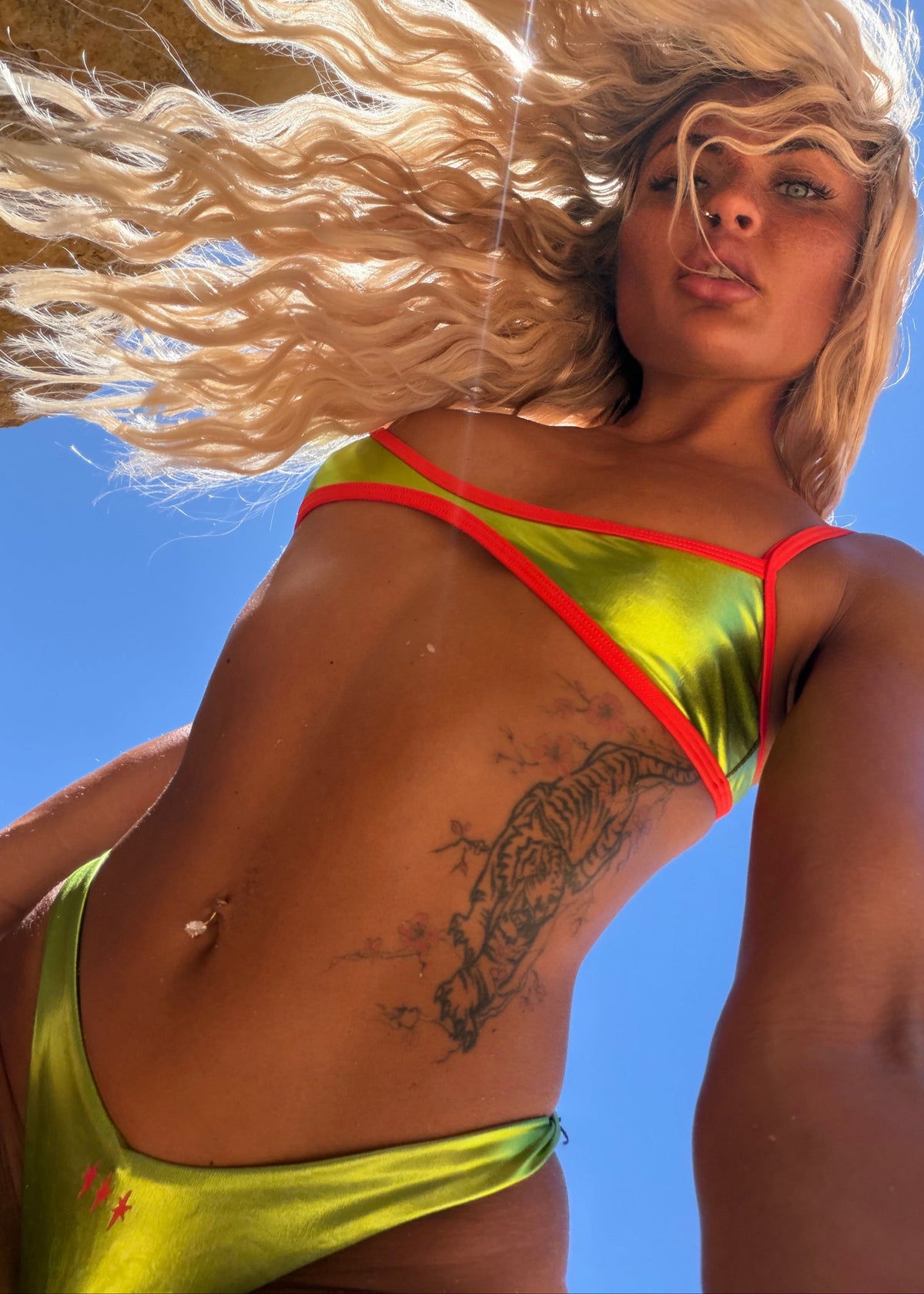 Woman in a green bikini with red straps against a clear blue sky