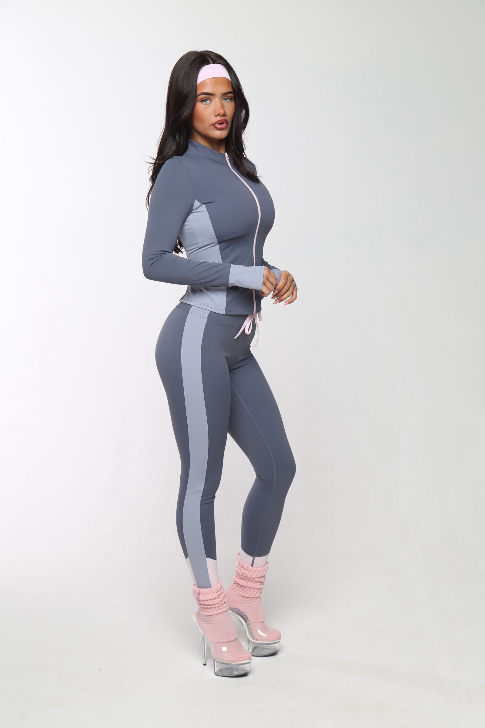 Woman in a gray athletic outfit with pink shoes on a white background
