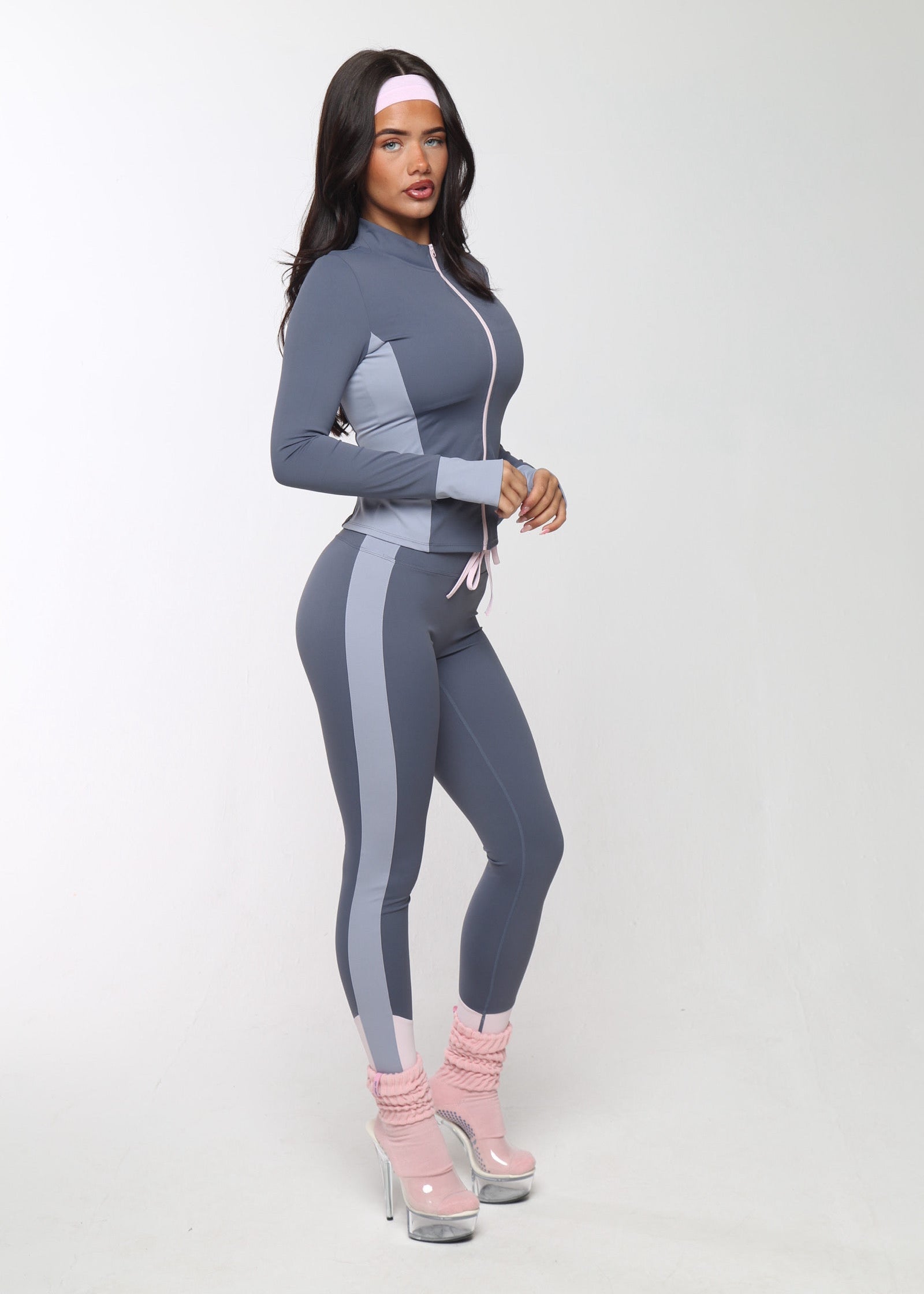 Woman in a gray athletic outfit with pink shoes on a white background