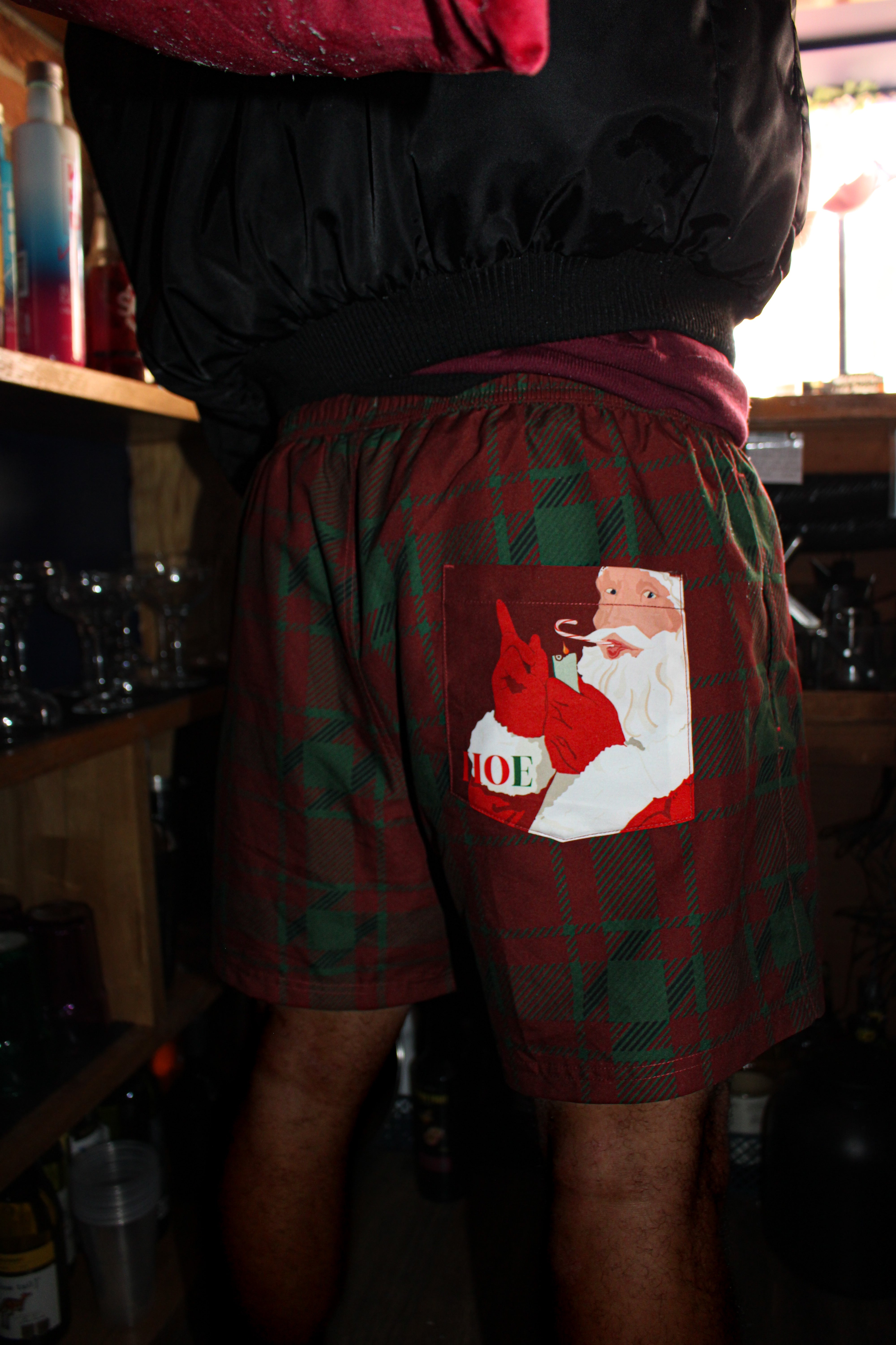 Person wearing a pair of plaid shorts with a Santa Claus graphic and 'HOE' text.