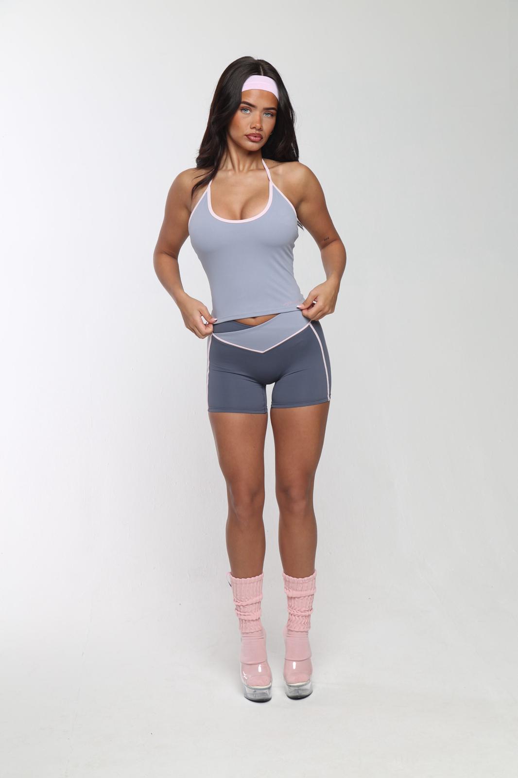 Woman wearing a gray athletic outfit with pink socks on a white background