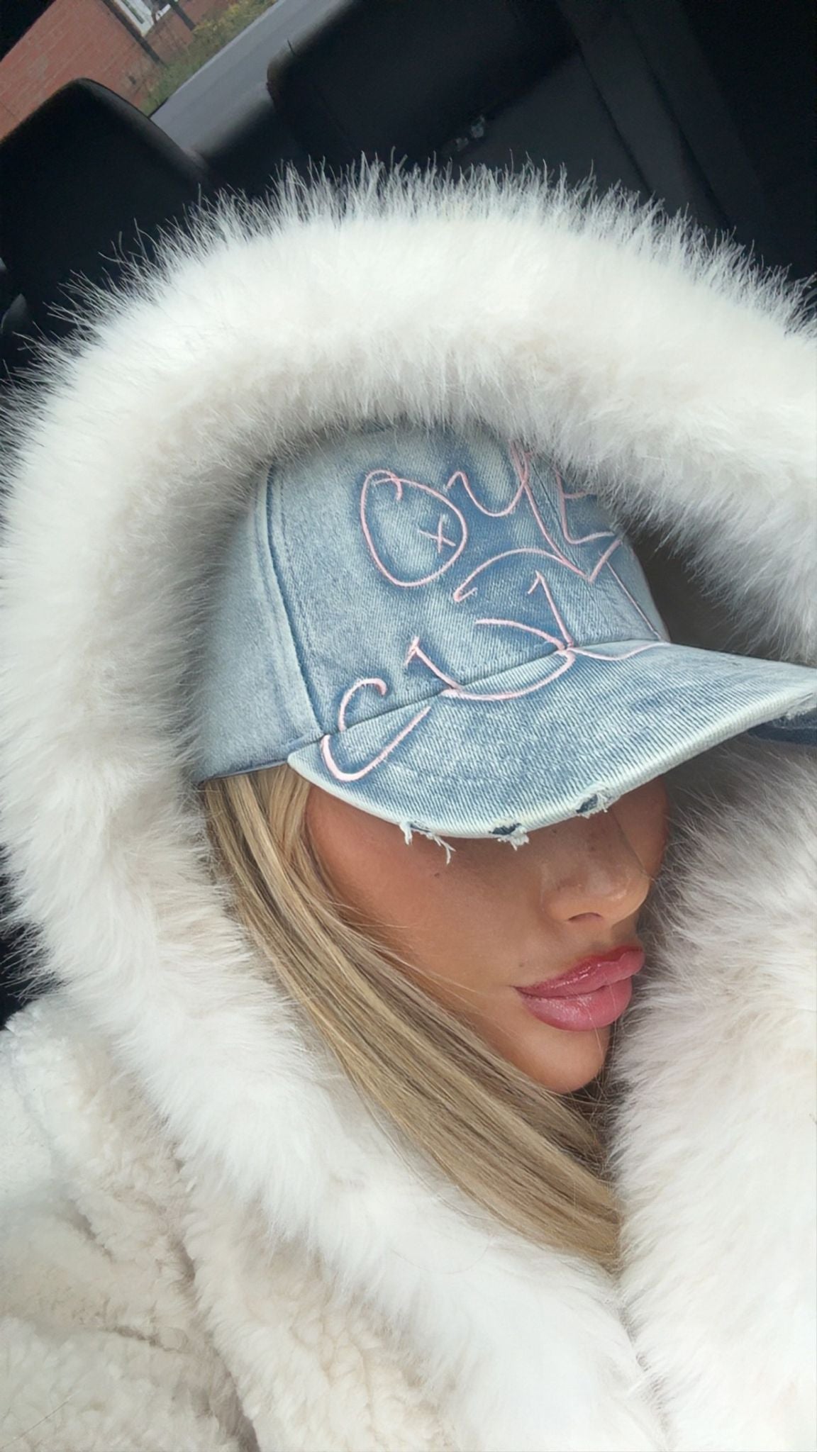 Person wearing a denim cap with white fur trim and a white coat.