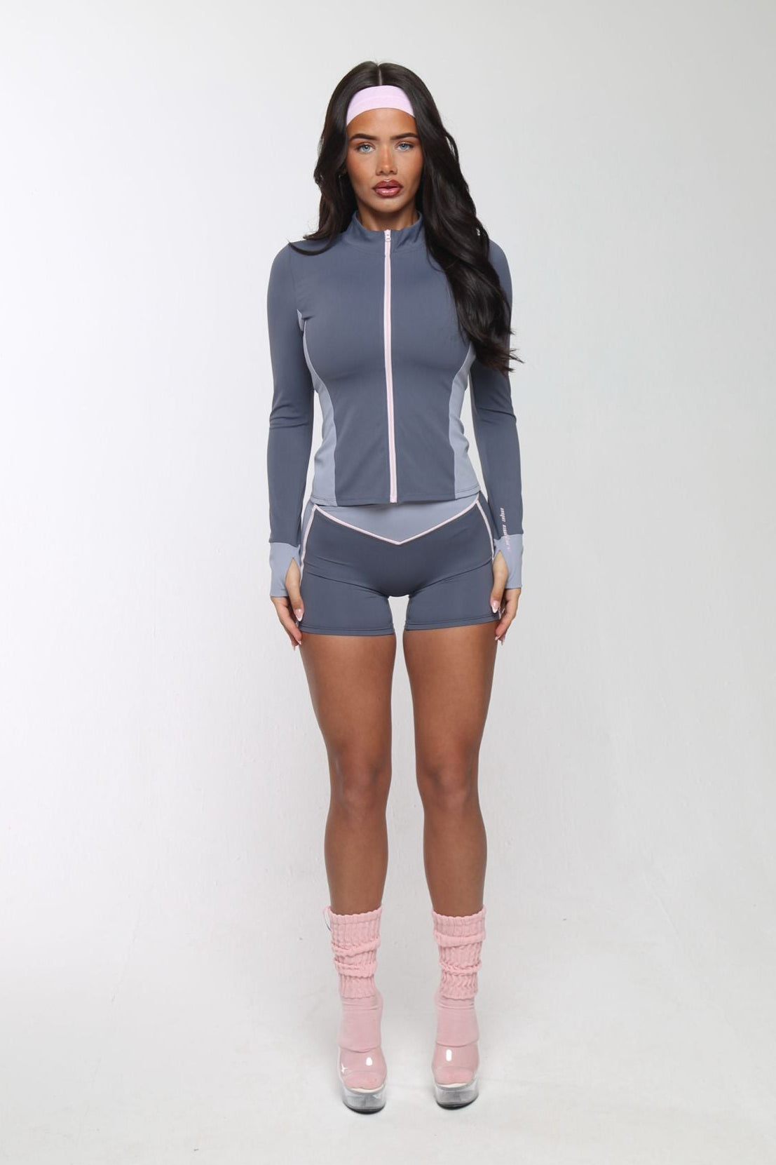 Woman wearing a gray athletic outfit with pink socks on a white background